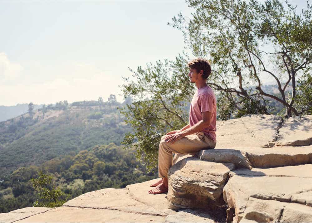 a man meditating on a mountain ledge
