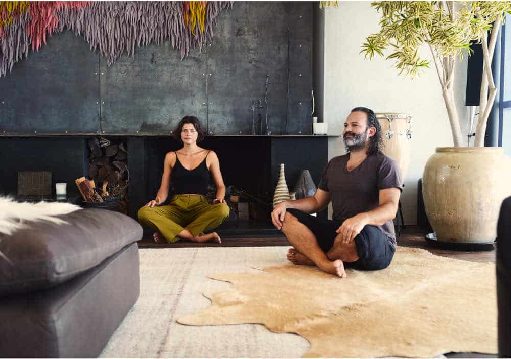two individuals sitting cross legged on the floor meditating