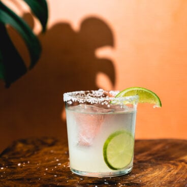 Tequila cocktail in glass with lime wedge and salt rim.