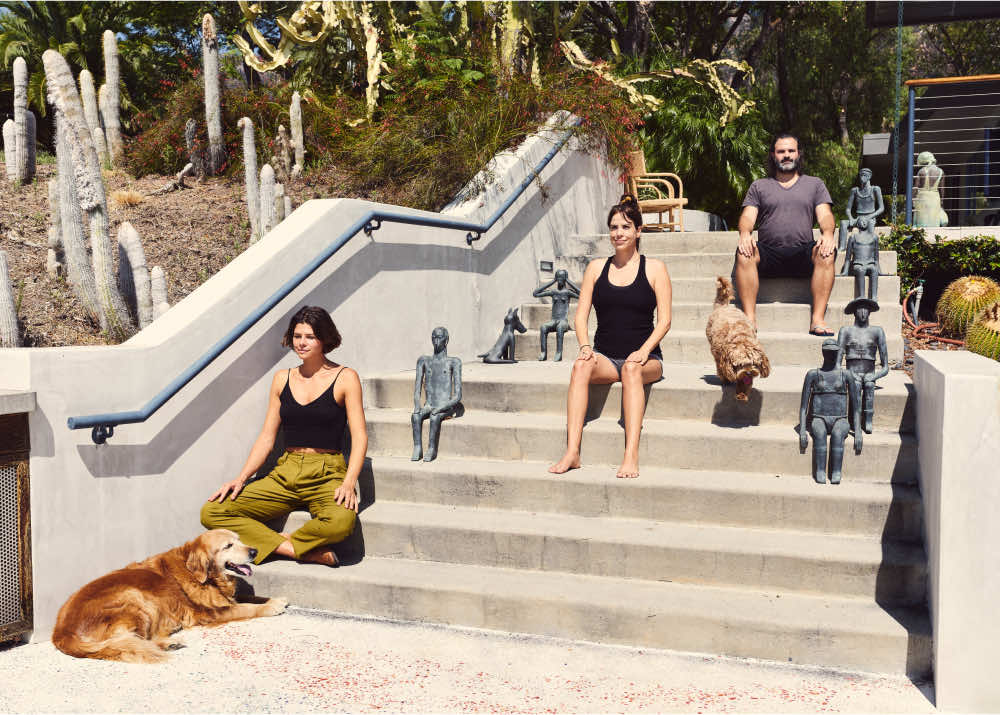 3 people meditating on steps with two dogs.